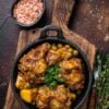 Beef oxtails stew with wine and vegetables in a pan. Dark background. Top view