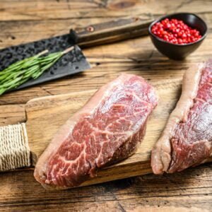 Raw rump cap steak on a chopping Board. wooden background. Top view